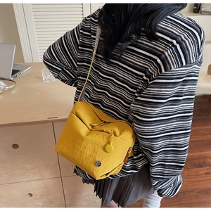 Detailed macro view of vibrant yellow nylon crossbody bag with colorful woven shoulder strap