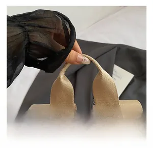 Detail of khaki nylon backpack featuring thick webbed handle and silver metal zipper puller