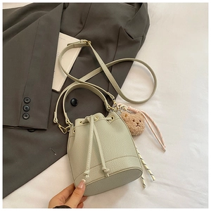 Detail of mint green bucket bag featuring pebbled texture and plush bear charm