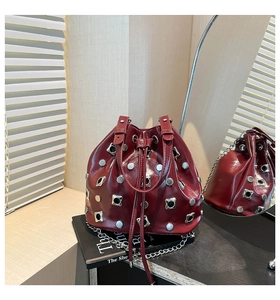 Macro shot of burgundy patent leather bucket bag with silver studs and chain strap