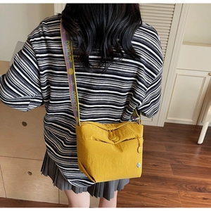 Detail of yellow canvas crossbody bag featuring a wide jacquard strap and zipper pocket