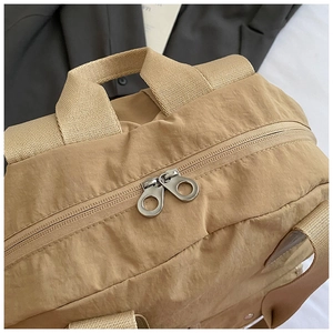 Detail of dual silver zippers and nylon fabric texture on khaki travel backpack
