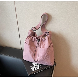 Detail of pink nylon bucket bag with black drawstring closure and adjustable shoulder strap