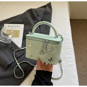 Detail of light green bow box bag with silver butterflies and leather chain strap