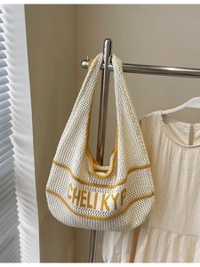 Minimalist knit tote bag with yellow stripes and openwork crochet texture hanging on a rack