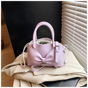 Détail d'un mini sac seau lilas avec grand nœud et pendentif en forme de cœur