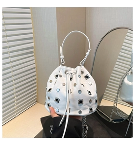 Detailed view of white bucket bag featuring silver eyelets, rivets, and chain strap