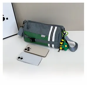 Comparaison de taille d'un sac cylindrique en nylon à carreaux avec deux smartphones