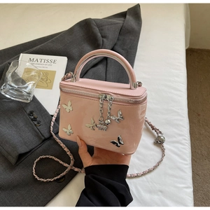Detail of pink bow-shaped embossed box bag with silver metal charms and chain strap