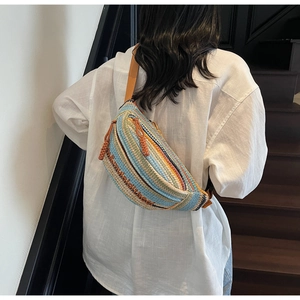 Detail of bohemian striped woven crossbody bag showing leather zipper pulls and texture