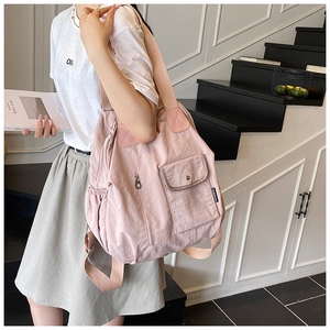 Detail view of pink nylon multifunctional backpack with wide canvas straps and pockets