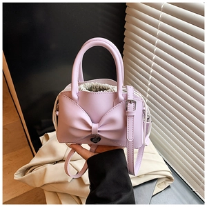 Détail du sac à main violet à nœud avec pendentif cœur et doublure à cordon crème