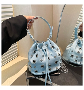 Close-up of light blue studded bucket bag with metallic rivets and drawstring closure