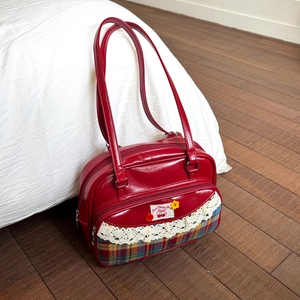 Detailed macro view of the sweet cherry print and lace trim on the red tote bag surface