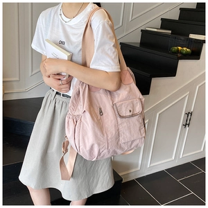 Detailed close-up of a pink nylon tote bag showing functional side pockets and wide straps