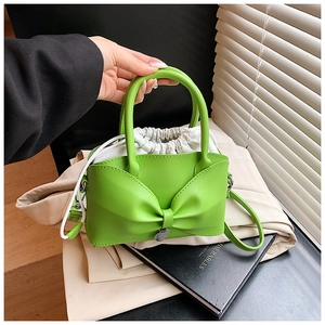Détail du sac seau vert vif avec nœud décoratif et pochette intérieure à cordon