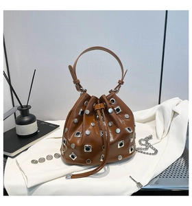 Detail of brown glossy bucket bag with silver studs and a metallic chain strap
