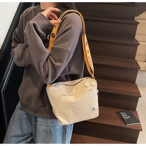 Detail of beige canvas crossbody bag featuring yellow floral woven strap and zip closure