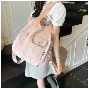 Macro side view of light pink nylon multi-pocket backpack showing adjustable shoulder straps