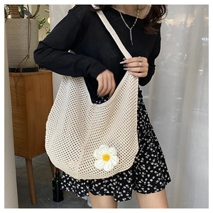 Détail d'un sac hobo tissé beige avec motif ajouré et décoration de fleur de marguerite