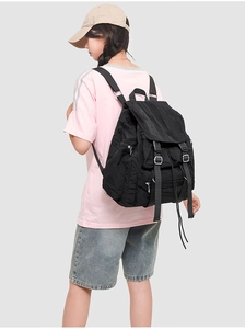 Détail d'un grand sac à dos en nylon noir avec plusieurs poches et boucles sur le mannequin