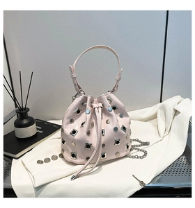 Detail of pink rivet bucket bag with silver studs and chain strap on a stylist set