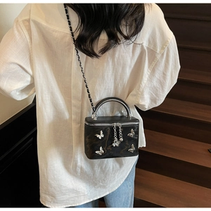 Detail showing the silver butterfly ornaments and chain strap on this black crossbody bag