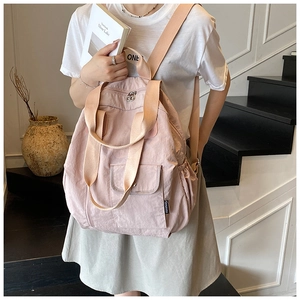 Detail of light pink nylon backpack featuring functional side pockets and textured fabric