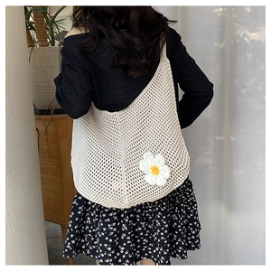 Détail d'un sac cabas tissé beige orné d'une décoration florale de marguerite blanche en 3D