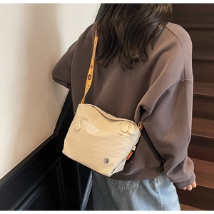 Detailed back view of a beige nylon crossbody bag with vintage patterned wide strap