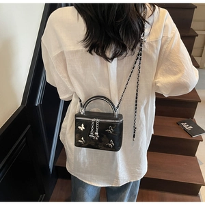 Detailed shot of black box crossbody bag featuring five silver 3D butterfly ornaments