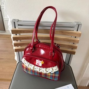 Close-up of red patent leather tote with plaid fabric and sweet cherry patch detail
