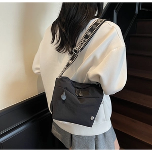 Rear view of model wearing a black casual crossbody bag with decorative jacquard wide strap