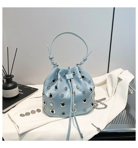 Close-up of light blue bucket bag with silver studs, metal grommets and chain strap