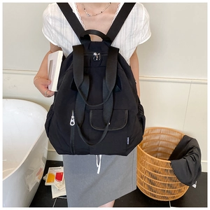 Detail of a versatile black nylon backpack with top handle and multiple front zip pockets
