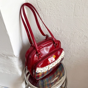 Detail of red patent leather tote with lace trim and Scottish plaid patchwork fabric