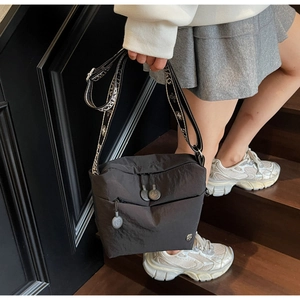Detail of black nylon crossbody bag with wide jacquard strap and functional pockets