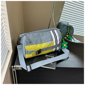 Détail du sac à bandoulière en nylon quadrillé avec panneau jaune et charme fleur verte