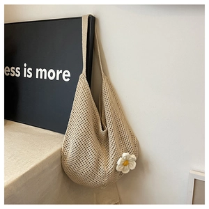 Détail d'un sac fourre-tout en crochet beige orné d'une petite fleur de marguerite
