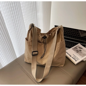 Detail of large khaki tote bag with drawstring side pocket and adjustable shoulder strap