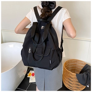 Detail showing the adjustable shoulder straps and side label of this black nylon backpack