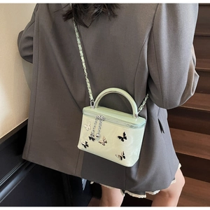 Detail of mint green box bag with butterfly appliques and metallic chain strap