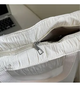 Detail view of the silver metal zipper and white pleated fabric on a large tote bag