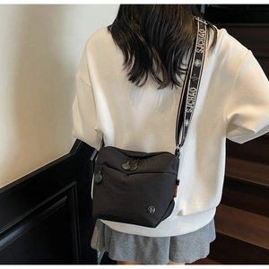 Detail of black nylon crossbody bag with printed wide shoulder strap and metal logo