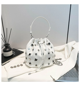 Close-up of white leather bucket bag featuring silver rivet studs and drawstring closure