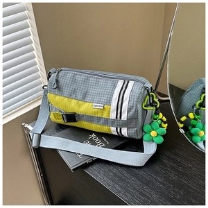 Détail du sac polochon en nylon gris avec empiècement jaune et breloque fleurie