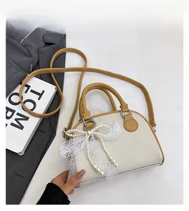 Detail of beige lychee pattern Boston bag with white lace bow and pearl decoration