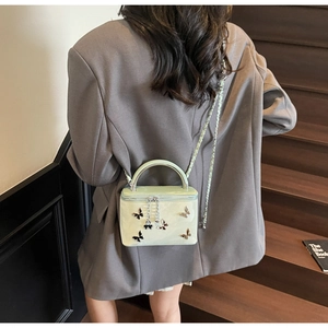 Chic mint green crossbody box bag with bow detail shown on model in a classic setting