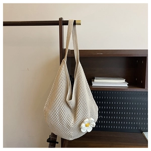 Détail du cabas en maille beige avec ornement de fleur blanche et bandoulière large