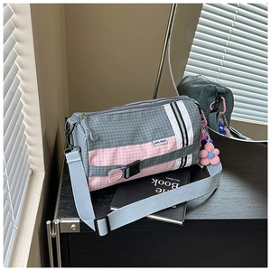 Détail du sac polochon en nylon à carreaux avec boucles sportives et pendentif fleur